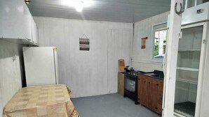 A compact kitchen with a table, a refrigerator, a stove, and a microwave. - Country House with Waterfall and Pool - Maciambu Waterfall - Country House (Enseada de Brito)