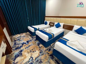 A hotel room with two beds, a patterned carpet, and a blue curtain. - Zad Al-Mashaer Hotel (Makkah)
