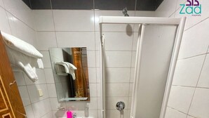 Un baño con lavamanos, inodoro y cabina de ducha con mampara de vidrio.