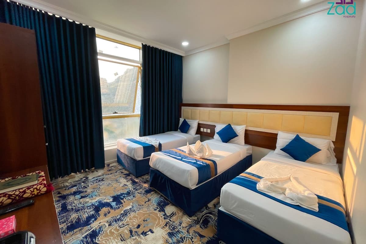Ein Hotelzimmer mit zwei Betten, einem großen Fenster und einem gemusterten Teppich.
