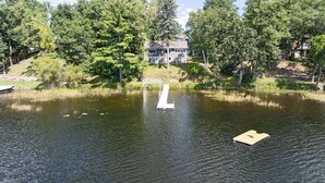 Une maison avec un quai qui s’avance sur un lac, le tout entouré d’arbres.