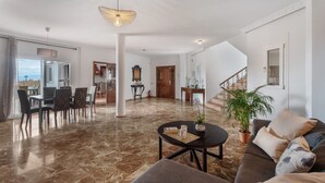Amplia sala de estar con piso de mármol, un sofá, una mesa de centro y un comedor con sillas y una mesa.