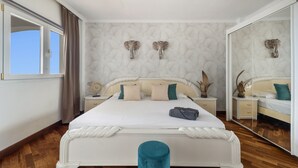 Un dormitorio con una cama grande, dos mesitas de noche, un espejo y una ventana con cortinas.