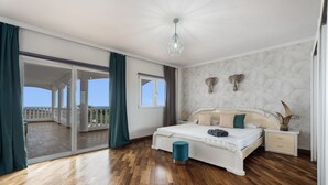 Un dormitorio con una cama grande, una mesita de noche, una ventana, un balcón y una lámpara en el techo.