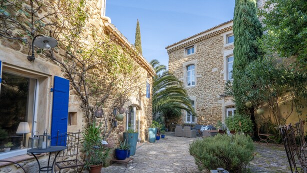 A courtyard with stone buildings, potted plants, outdoor furniture, and a clear sky. - Gîte 'Les Aiguières en Provence' with Private Terrace, Private Garden and Wi-Fi (Suze-la-Rousse)