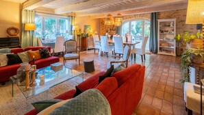A spacious living area with a red sofa, a glass coffee table, and a dining area with white chairs. - Gîte 'Les Aiguières en Provence' with Private Terrace, Private Garden and Wi-Fi (Suze-la-Rousse)