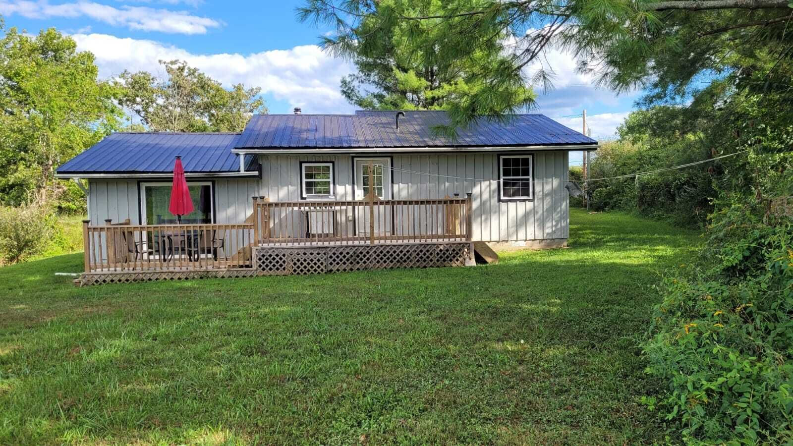 A single-story house with a fenced porch and a red umbrella.