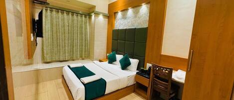 Une chambre d’hôtel avec un lit, un bureau, une chaise, une armoire et un rideau.