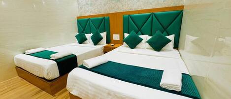 A hotel room with two beds, each with a wooden headboard and green bedding.