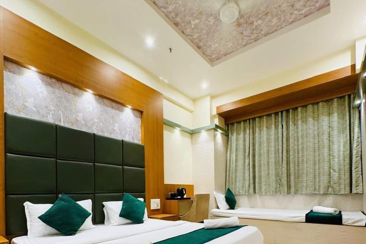 Een hotelkamer met een groot bed, een houten hoofdeinde, een plafondventilator en een raam met gordijnen.