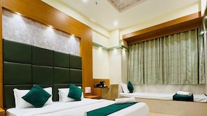 A hotel room with a large bed, wooden headboard, a ceiling fan, and a window with curtains.