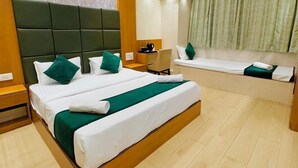 A hotel room with a large bed, a bedside table, a window with curtains, and a ceiling with a textured design.