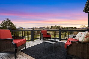 A deck with wicker furniture, a small table, and a view of the landscape.