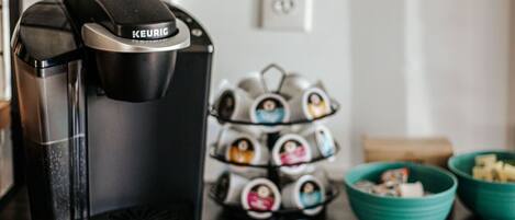 Eine Kaffeemaschine von Keurig auf einer Küchenarbeitsplatte, zusammen mit einem Becherhalter und zwei türkisblauen Schalen.