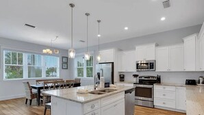 A modern kitchen with white cabinetry, stainless steel appliances, and a central island.