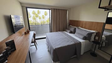 A hotel room with a large bed, a desk, a chair, a small table, and a TV.
