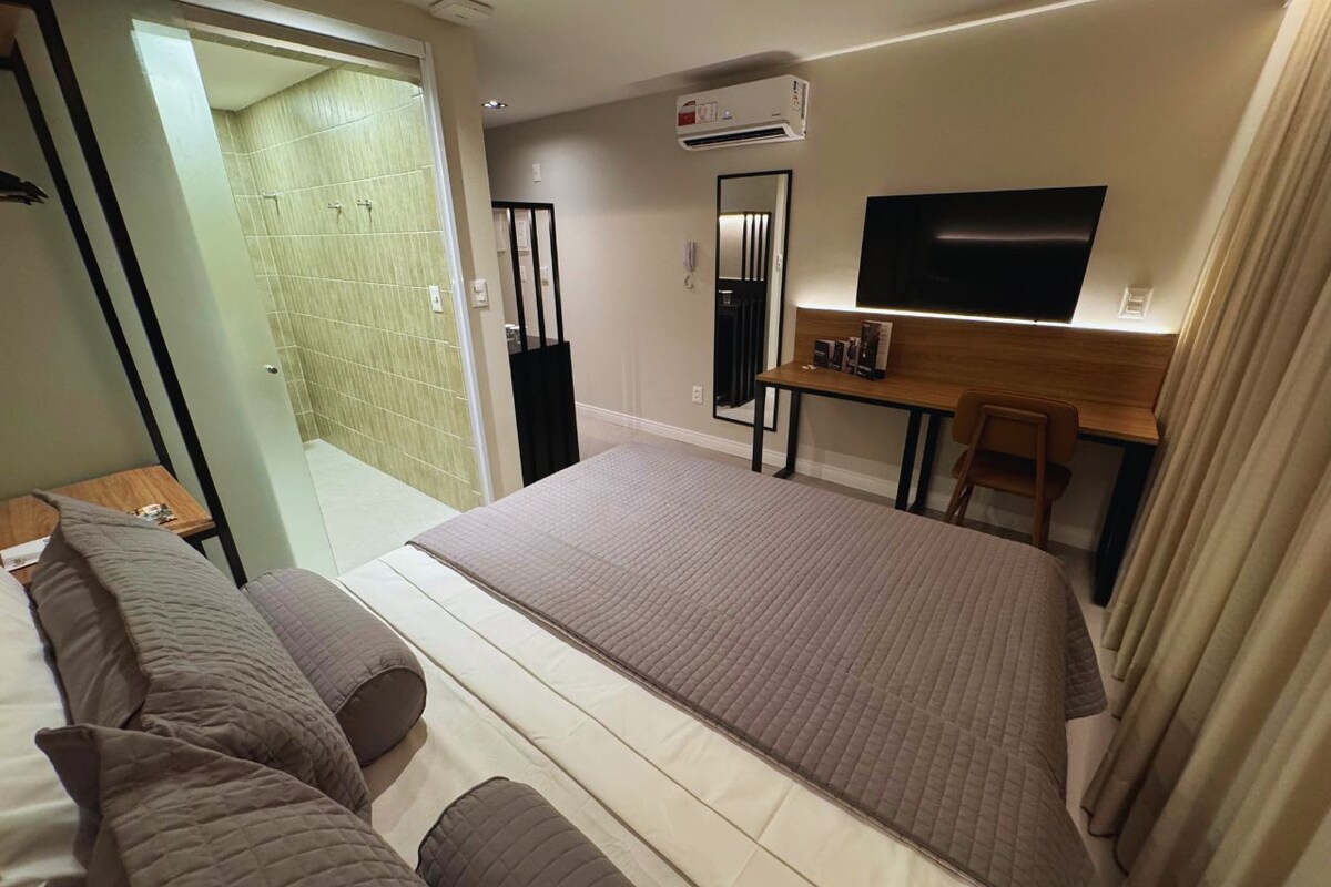 Une chambre d’hôtel avec un grand lit, un bureau avec une chaise, un téléviseur à écran plat et un miroir.