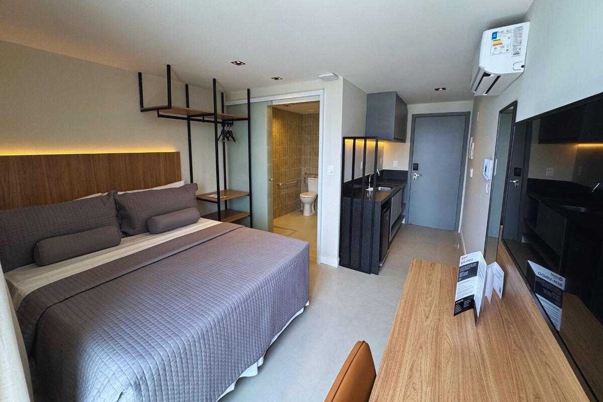 Una habitación de hotel moderna con una cama grande, un escritorio, un televisor y un baño separado.