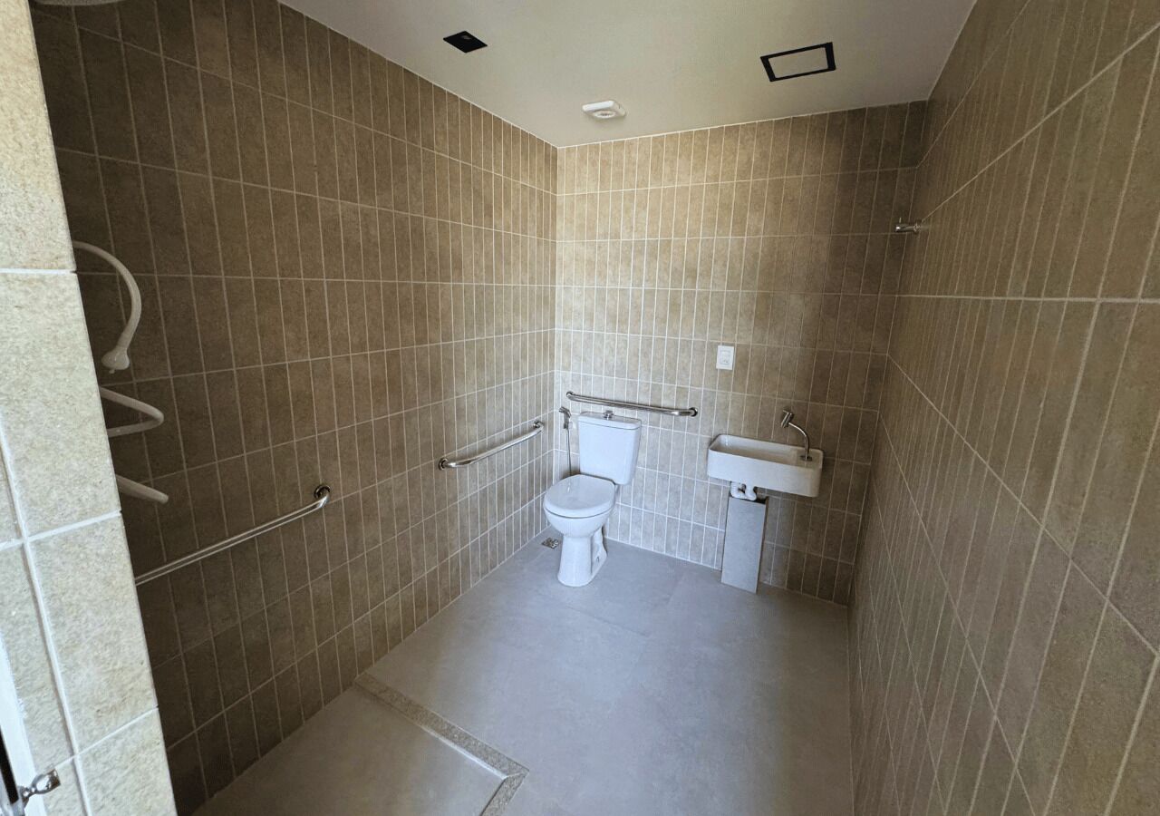 A small, tiled bathroom with a toilet, a sink, and a shower area.