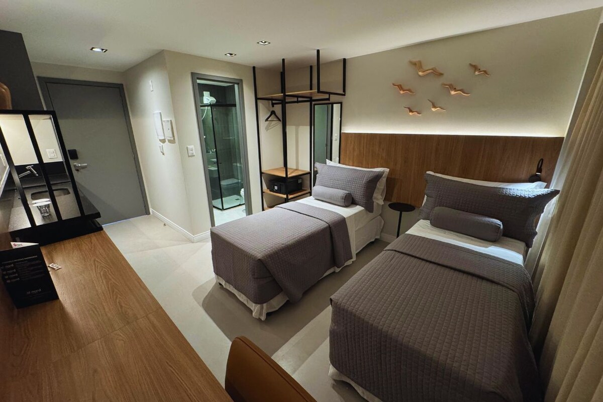 Une chambre d’hôtel moderne avec deux lits, un bureau en bois et une douche en verre.