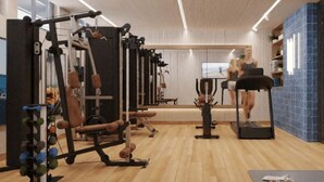 Ein Fitnessstudio mit unterschiedlichen Trainingsgeräten, Laufband und Spiegel.
