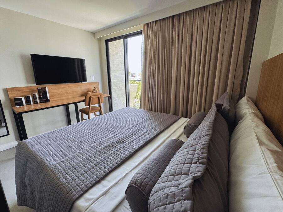 Habitación de hotel con una cama grande, un escritorio con televisión de pantalla plana y vistas al exterior mediante una puerta corrediza.