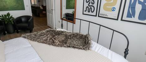 Een slaapkamer met een bed, een grote spiegel en kunst aan de muur.