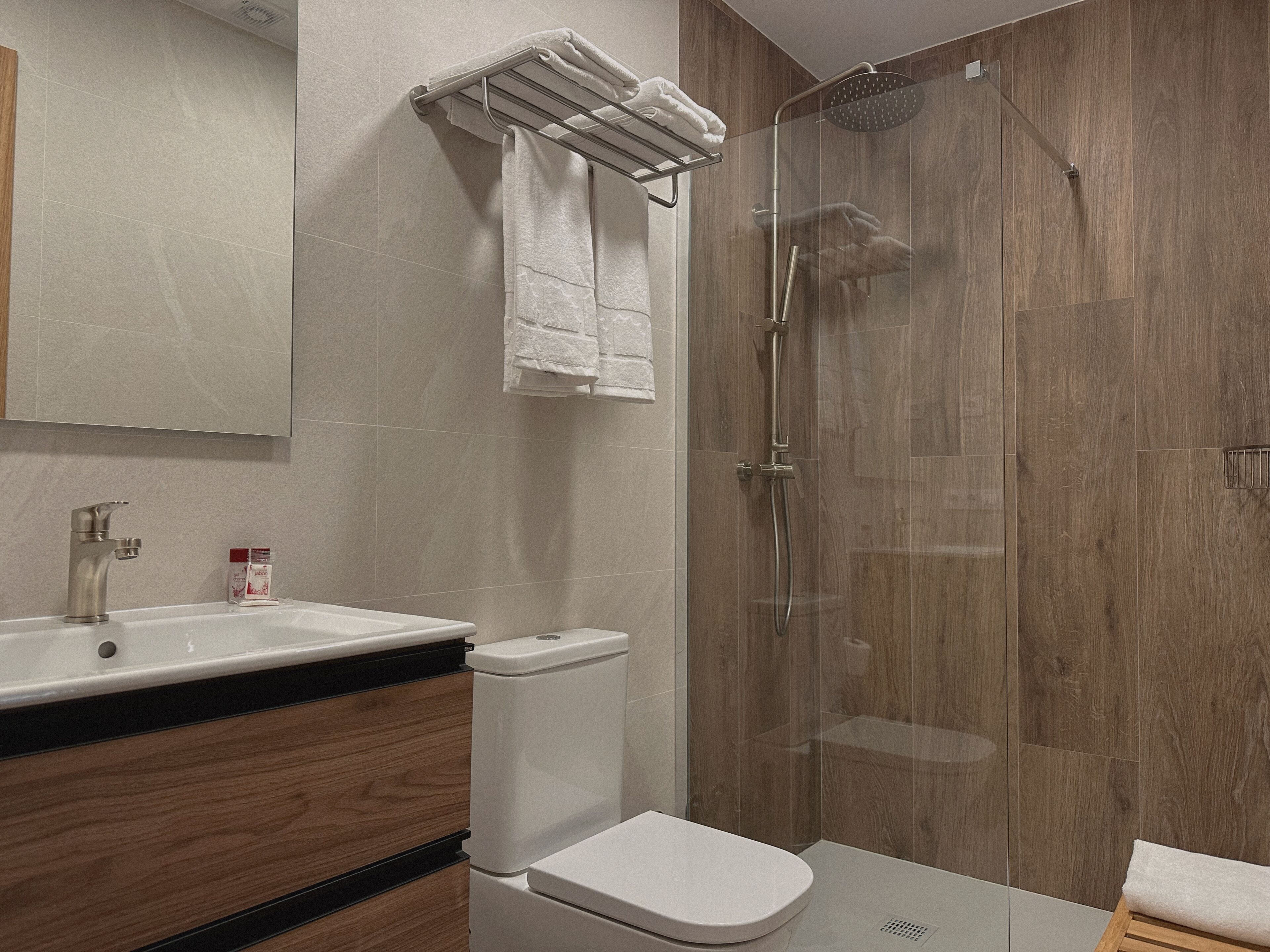 Een moderne badkamer met een douchecabine van glas, een wit wastafelmeubel en een toilet.