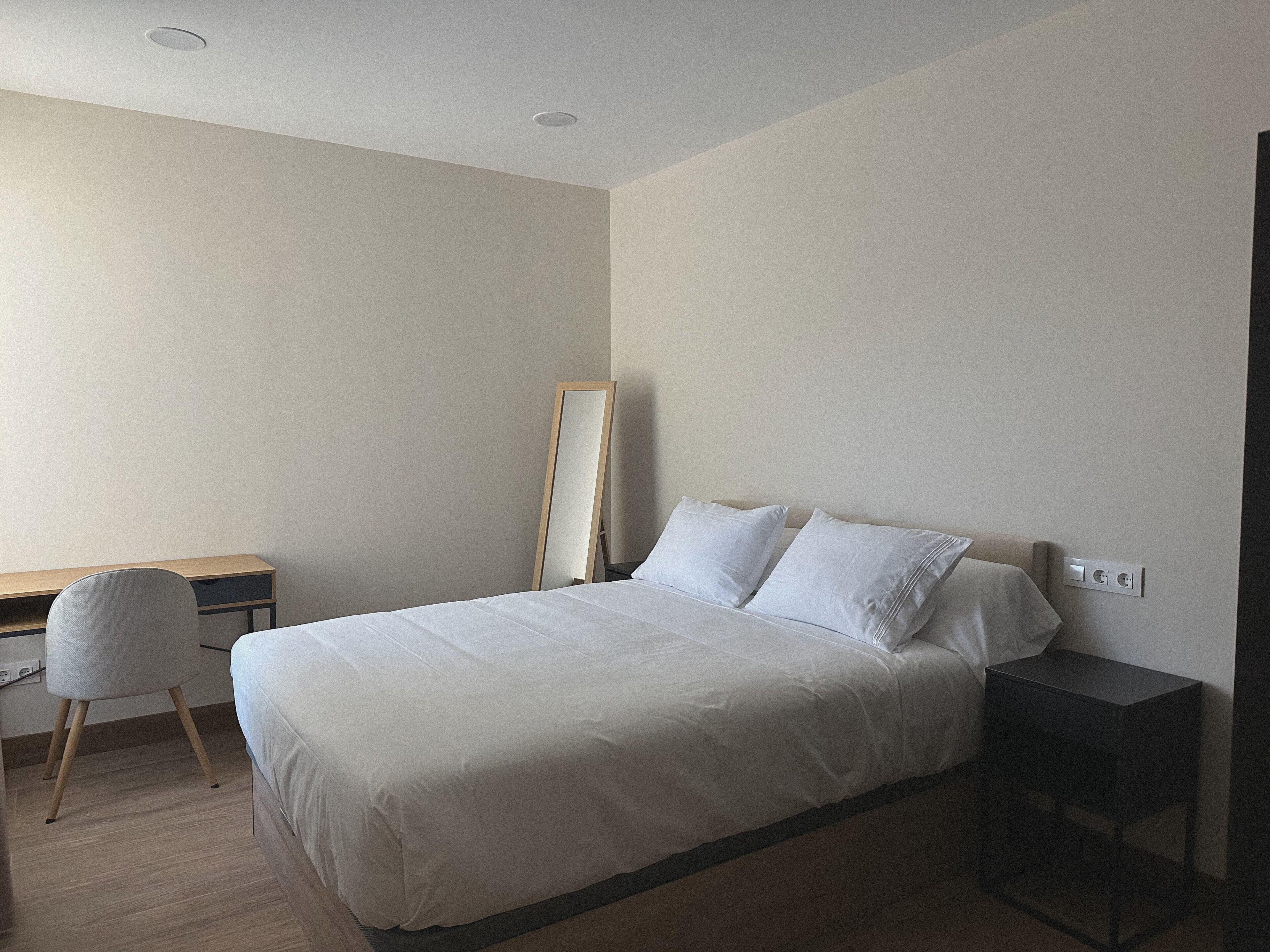 Un dormitorio con cama, escritorio, silla y mesita de noche.