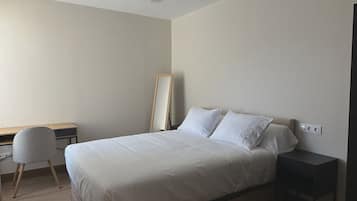 Un dormitorio con cama, escritorio, silla y mesita de noche.