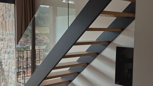 A modern staircase with glass railings and wooden steps. - El Balcón de Potes  (Potes)