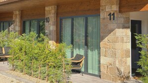 A hotel with numbered balconies, stone pillars, and a small outdoor seating area. - El Balcón de Potes  (Potes)