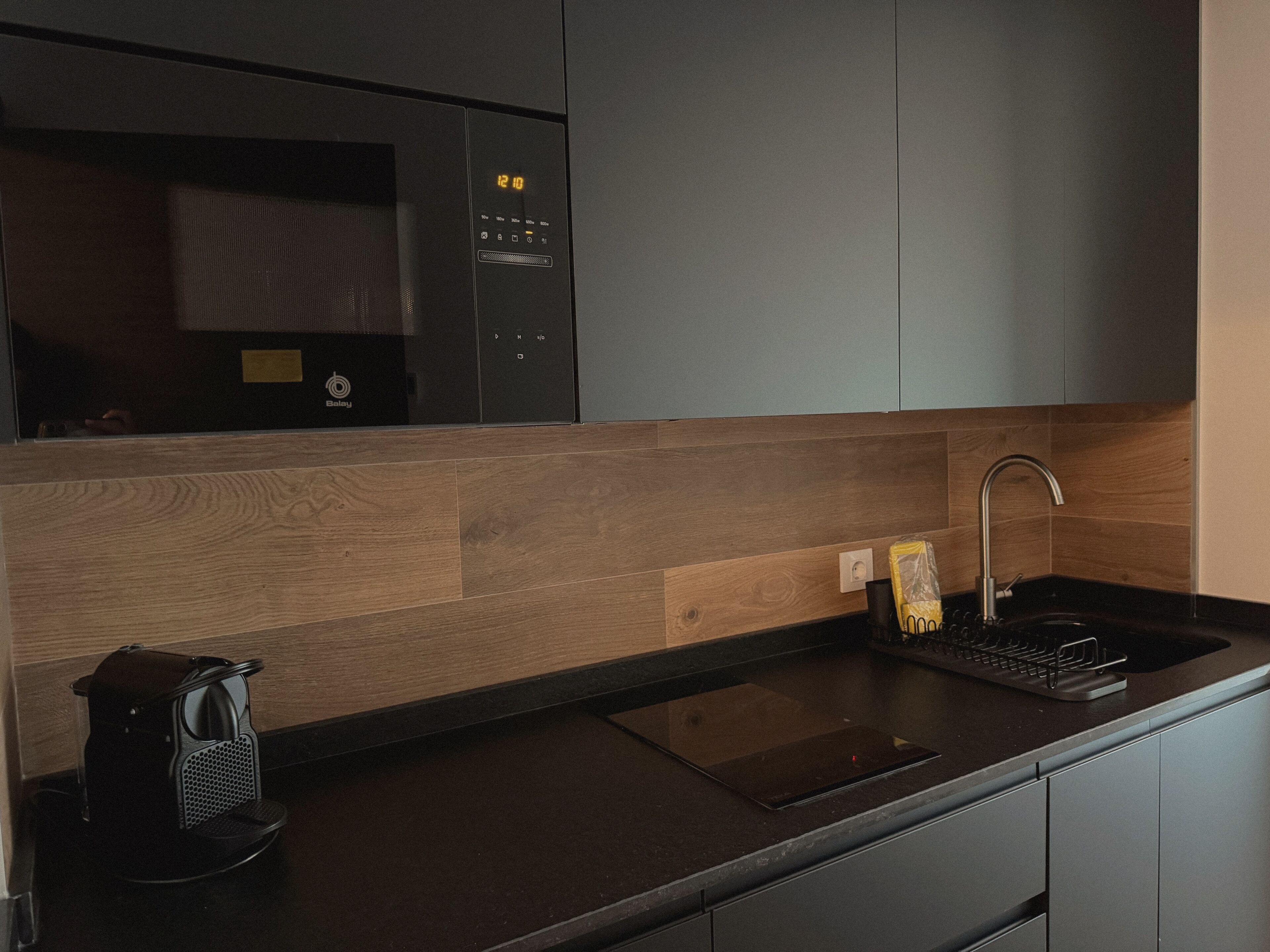 A modern kitchen with a built-in microwave, a sink, and a coffee maker.