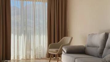 Una sala de estar con un sofá, un sillón y un ventanal con cortinas.