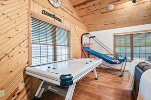 A pool table in a room with wooden walls and a ceiling.