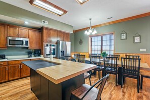 A kitchen with wooden cabinets, a central island, and a dining area with wooden chairs and a table.