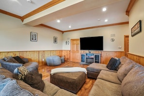 A living room with wooden paneling, a flat-screen TV, and a fireplace.
