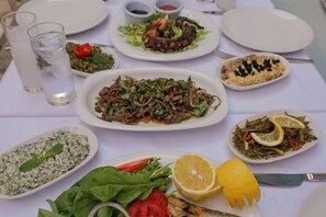 A table set with various dishes, including a salad, a fish dish, and a plate with a lemon wedge.