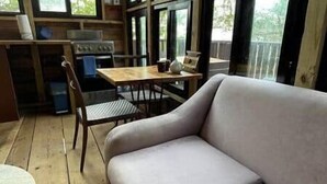 A wooden deck with a sofa and a dining table. - Unique Treehouse Cabin with Ocean Views on West End Negril; Romantic Escape (Westmoreland Parish)