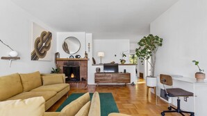 A modern living room with a fireplace, a sofa, a coffee table, and a dining area with a TV. - Two Bedroom Home Near the Freeway for Easy Access (San Francisco)