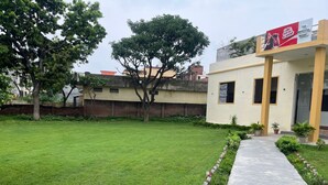 A hotel with a well-maintained lawn, a pathway leading to the entrance, and a Coca-Cola advertisement on the building.