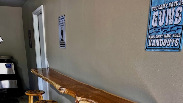 Una zona de bar con mostrador de madera y cuatro taburetes de madera.