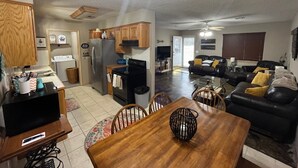 Un amplio espacio habitable con una mesa de comedor, cocina y un sofá de cuero negro.