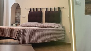 Habitació amb llit, taula petita i paret amb nínxecs allargats que contenen objectes decoratius.