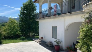 Un edifici amb un balcó, plantes en testos i vistes al paisatge.