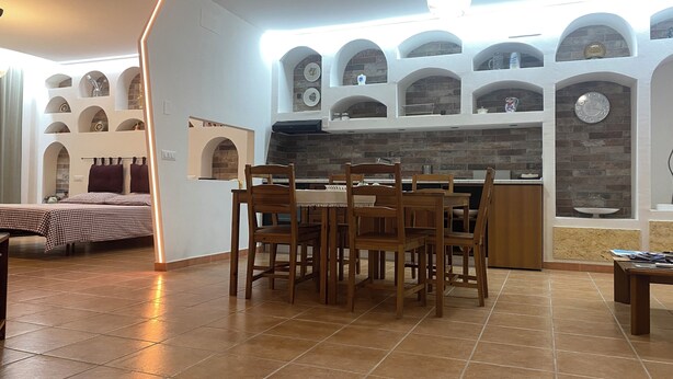 Cuina moderna amb zona de menjador, amb un mosaic de rajoles, parets blanques i un rellotge a la paret.
