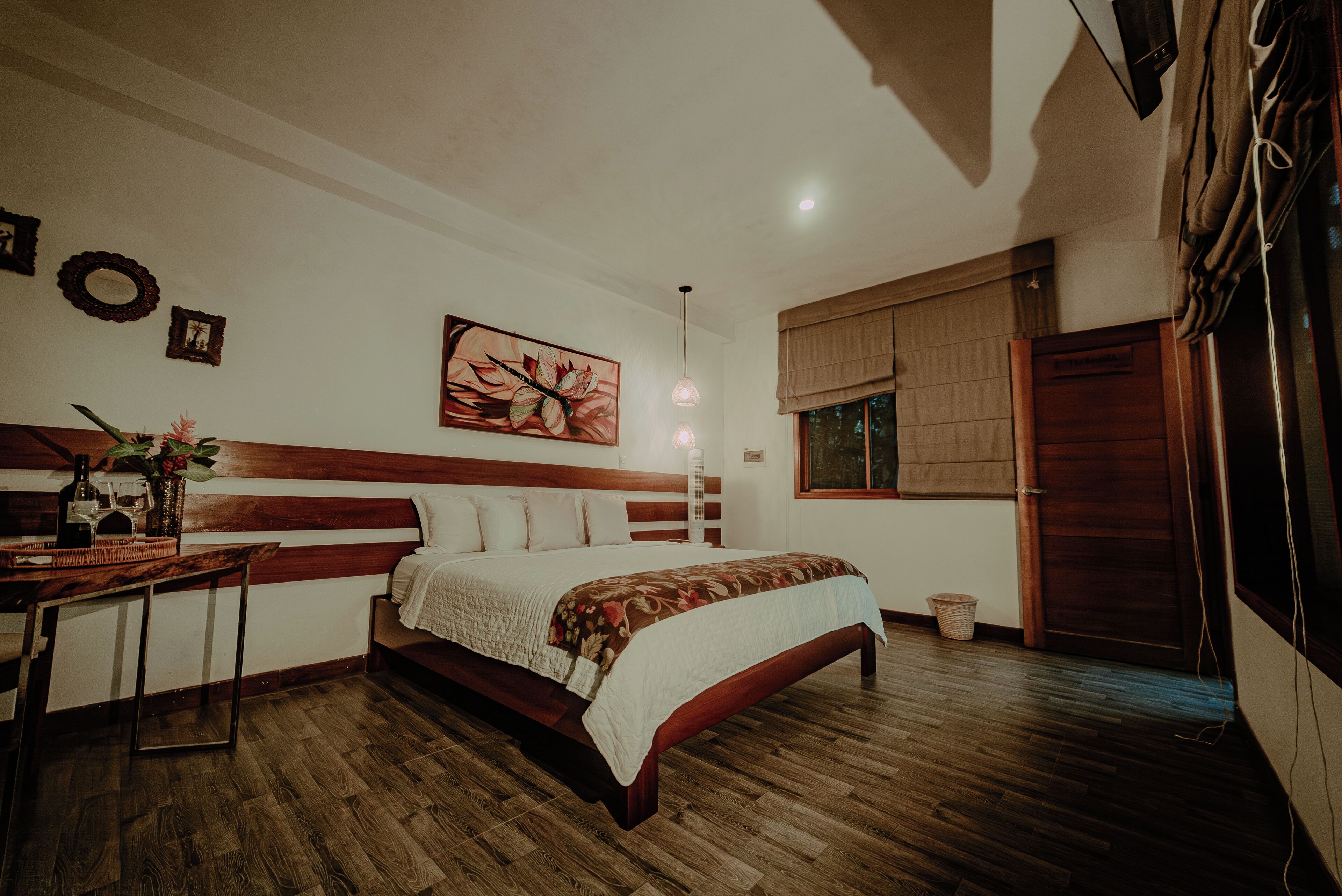 A bedroom with a wooden bed, a desk, and a large window with curtains.