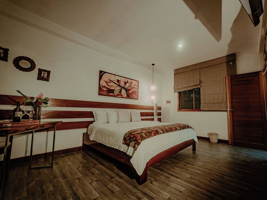 A bedroom with a wooden bed, a desk, and a large window with curtains.