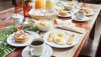 Una mesa de desayuno con tortitas, huevos y café.
