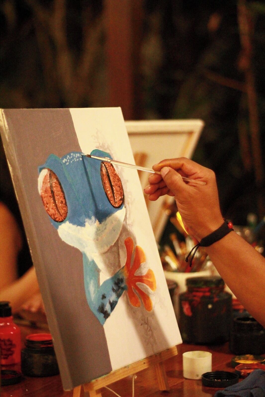A person painting a portrait on an easel.